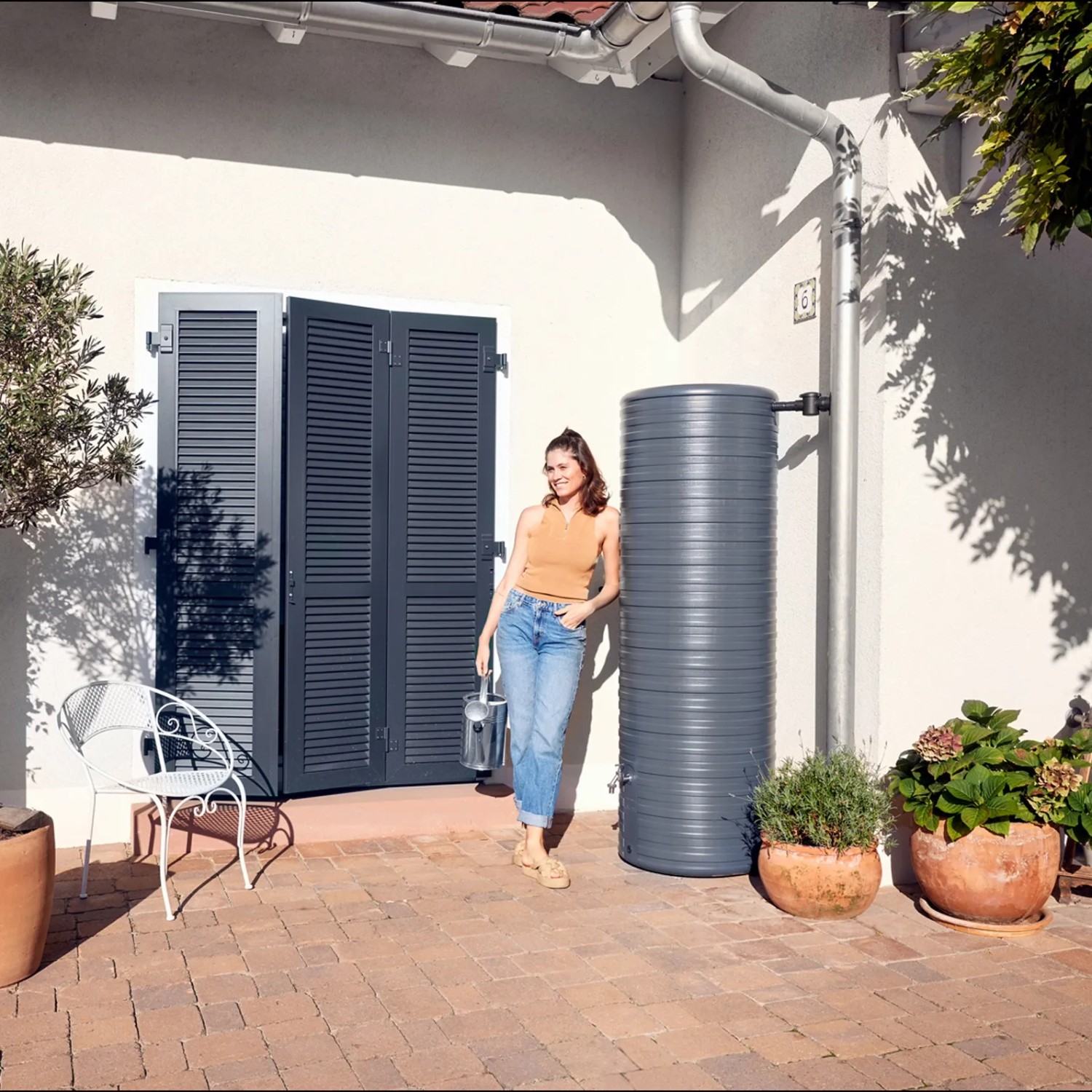 Garantia NORDIC Regenspeicher 500 l in Graphite Grey im Garten mit Frau. Schlichtes Design.