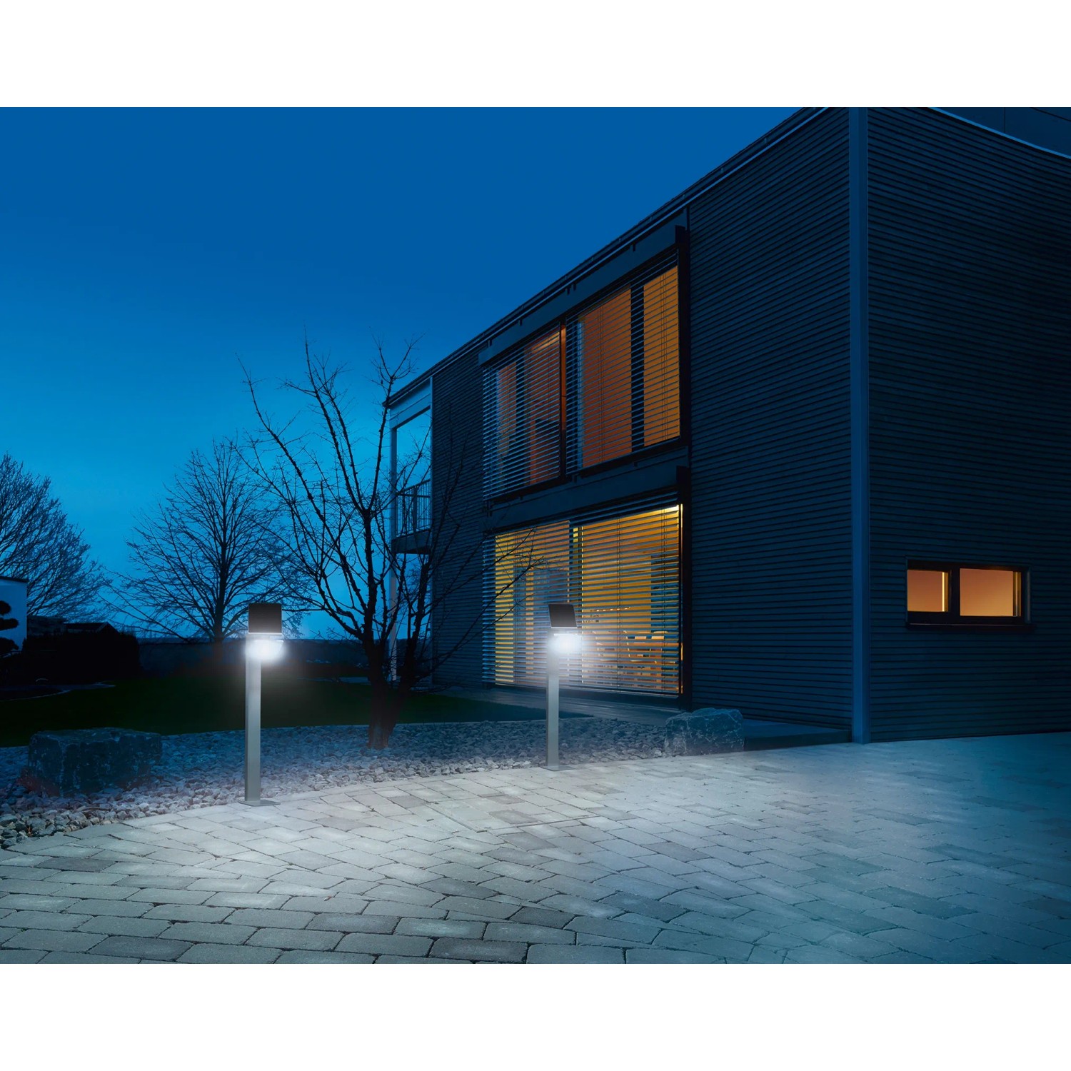 Silberne Steinel LED Solar Wegeleuchte XSolar GL-S beleuchtet einen Weg vor einem modernen Haus.