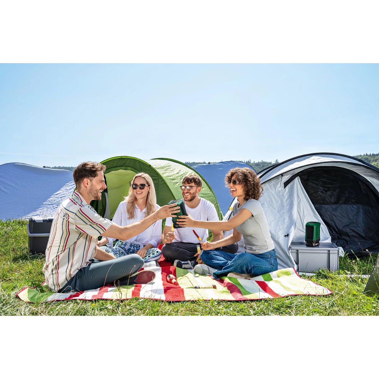 Dunkelgrüner Bosch UniversalSpeaker 18V-1 Bluetooth-Lautsprecher beim Camping mit Freunden. Kompaktes Akkugerät für Musik.