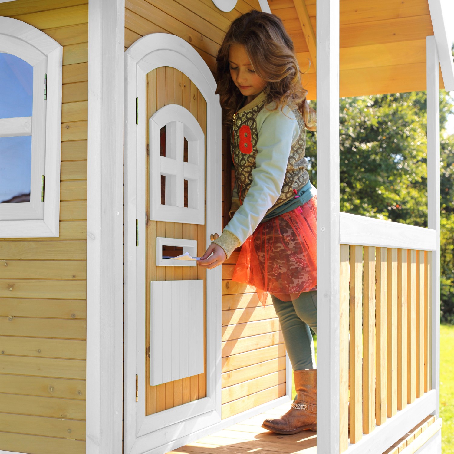 Mädchen steckt Brief in Briefkasten vom Axi Spielhaus Laura Braun/Weiß mit Rutsche Hellgrün.