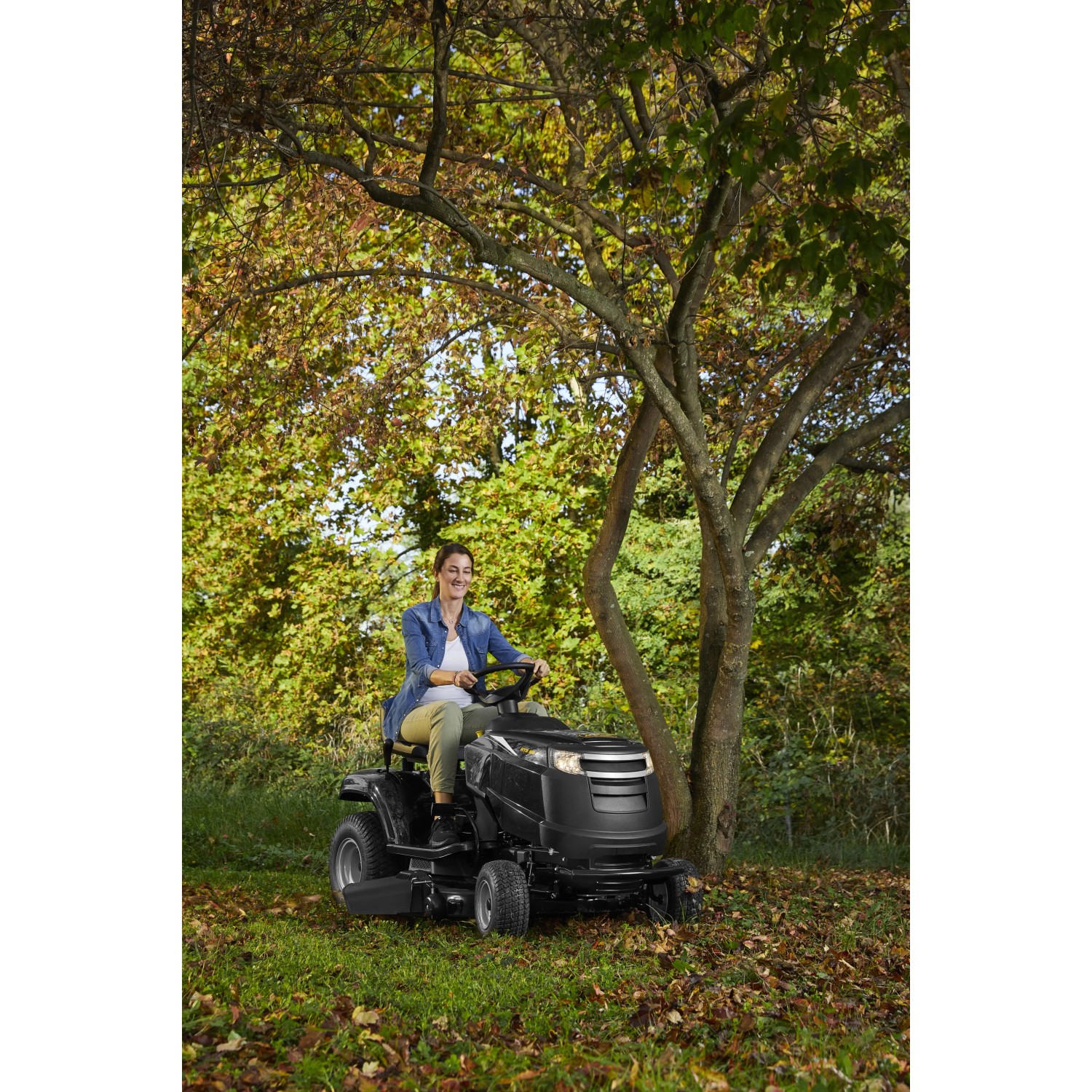 Schwarzer Alpina Rasentraktor AT3 98 A mit Fahrerin im Garten.