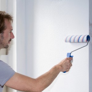 Mann streicht Wand mit Knauf Easy Putz Schneeweiß. Fertigputz mit feiner Körnung.