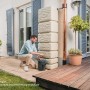 4rain Wandtank Slim Stone Decor 350 l Sandbeige mit Auslaufhahn in Anwendung im Garten.
