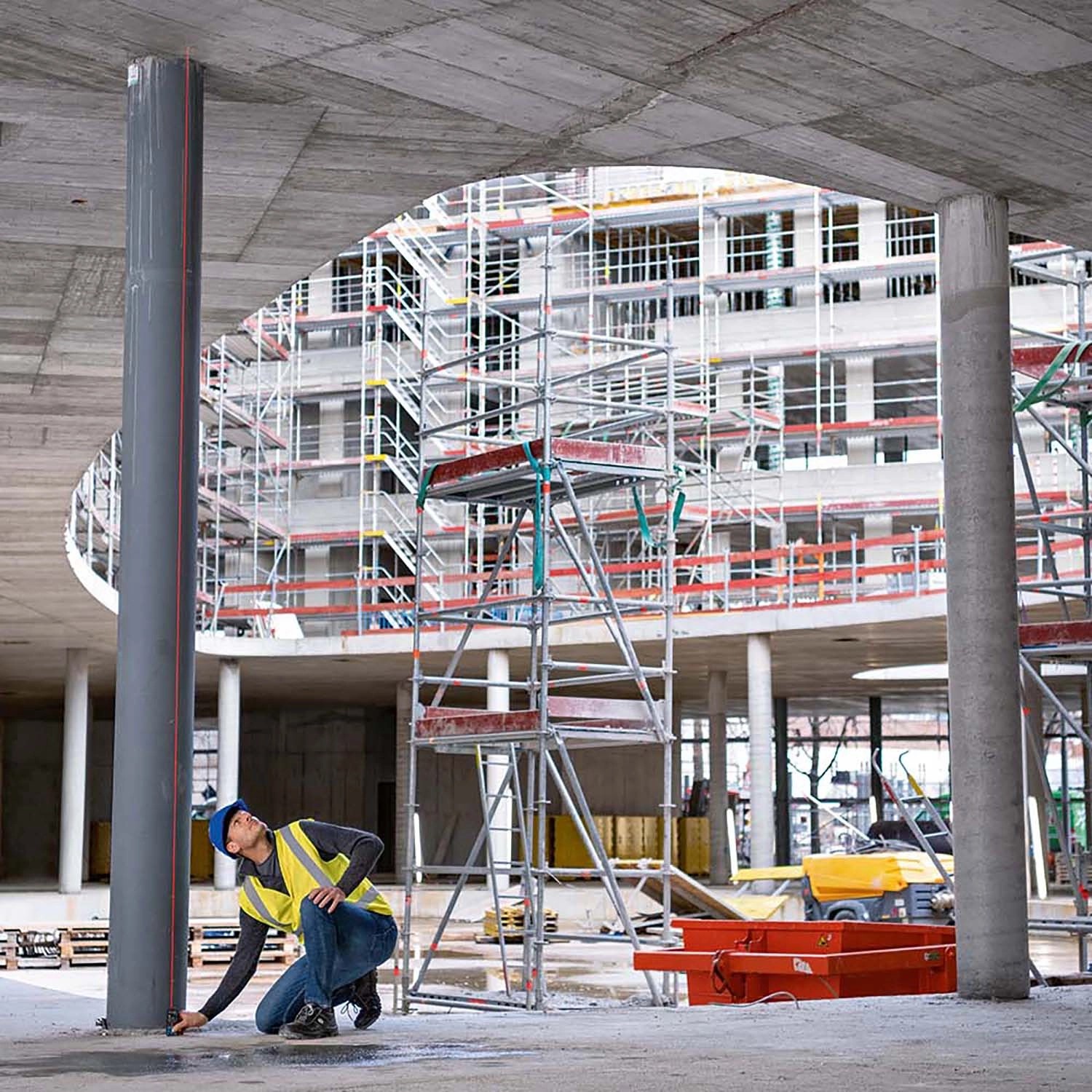 Handwerker misst mit Bosch Laser-Entfernungsmesser GLM 50-27 C einen Pfeiler auf der Baustelle.