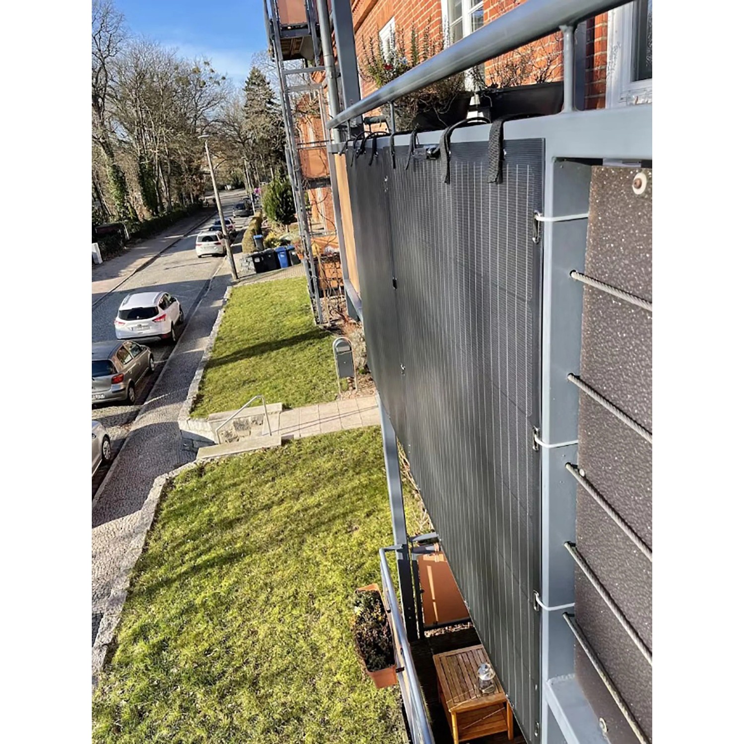 Flexibles Balkonkraftwerk 400W am Balkongeländer befestigt. Schwarze Solarpaneele mit Befestigungsbändern.