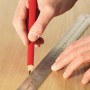 Bauheld Stahllineal 150mm im Einsatz: Hand zeichnet Linie mit Bleistift auf Holz.