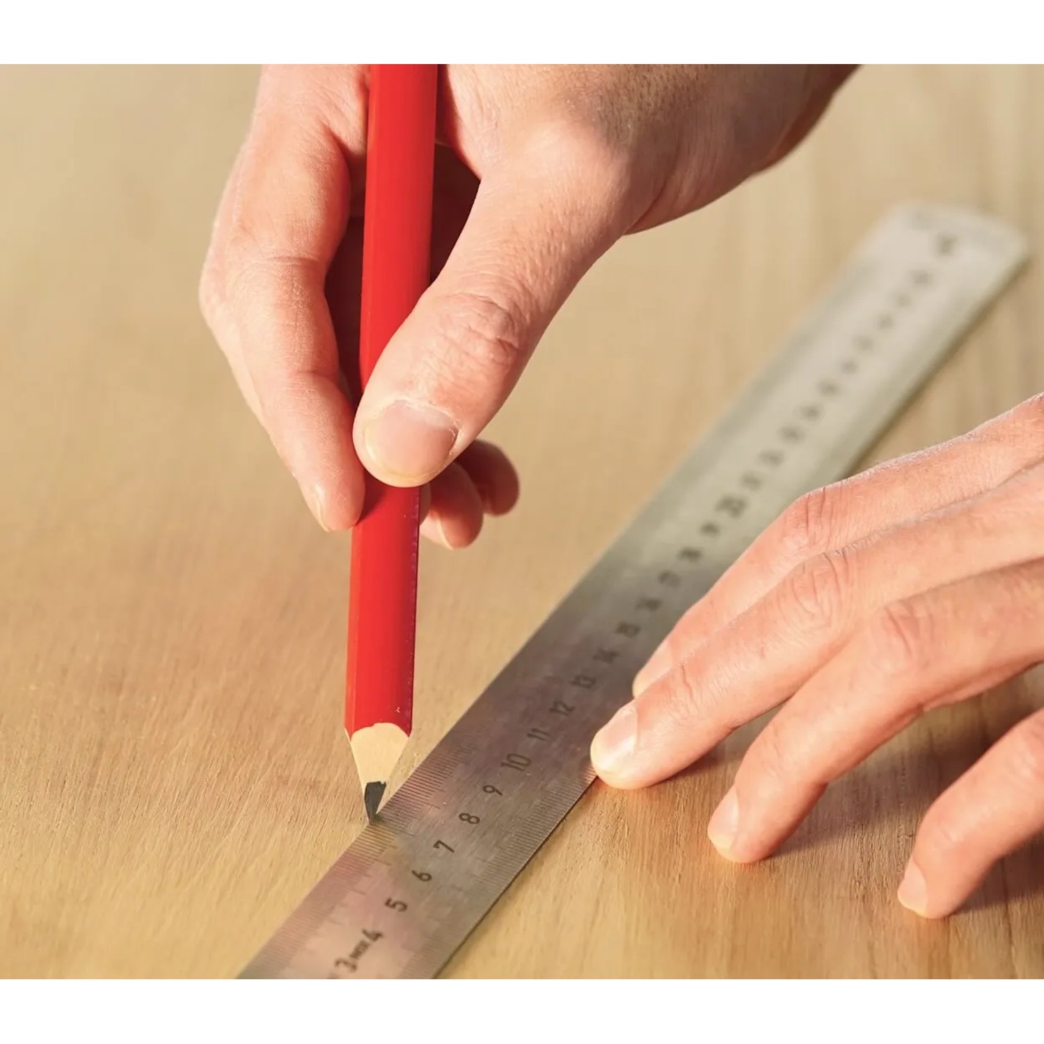 Bauheld Stahllineal 150mm im Einsatz: Hand zeichnet Linie mit Bleistift auf Holz.