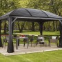 Anthrazitfarbener Sojag Pavillon Moreno 10x14 mit Moskitonetz und Gartenmöbeln auf Holzterrasse.