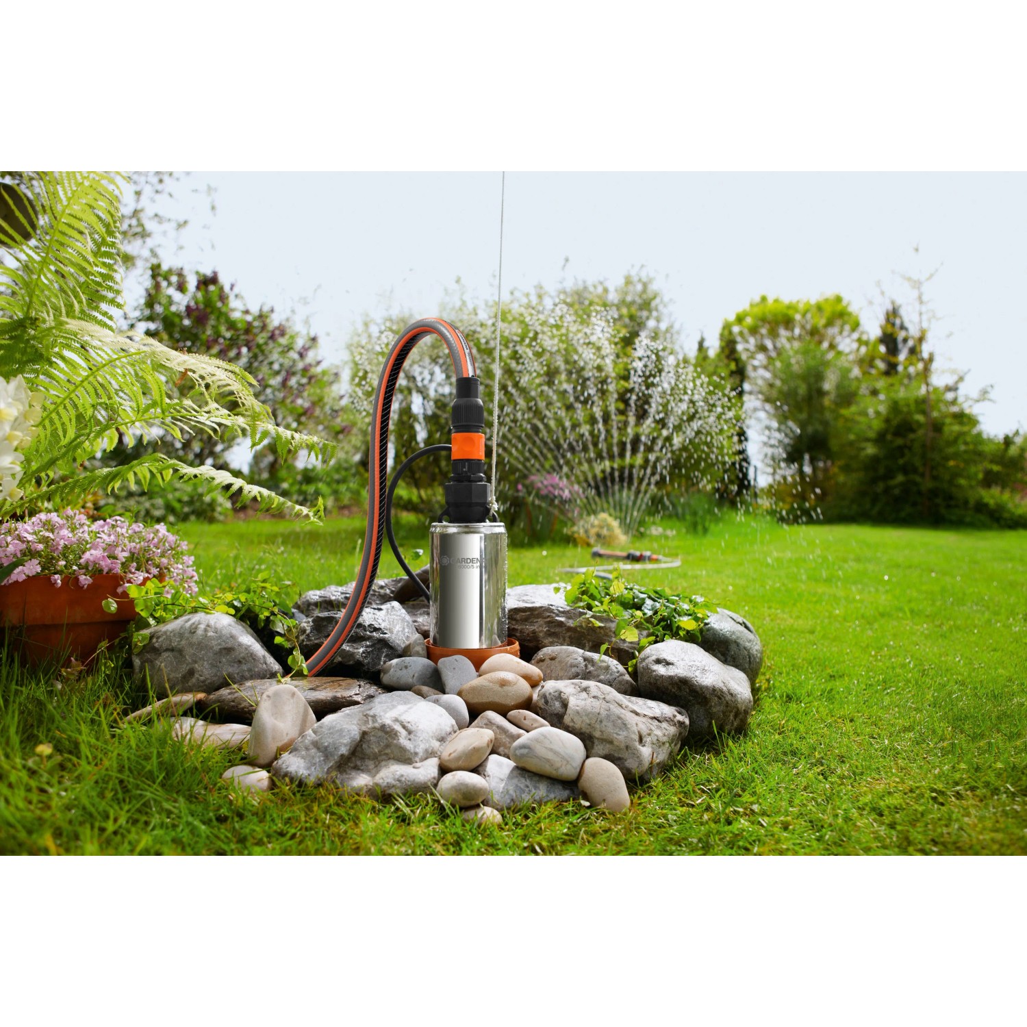 Gardena Premium Tiefbrunnenpumpe 6000/5 inox im Einsatz, Gartenbewässerung im Hintergrund.