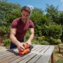 Mann schleift Tisch mit Black+Decker Schwingschleifer BEW220. Schleifmaschine in Orange und Schwarz.