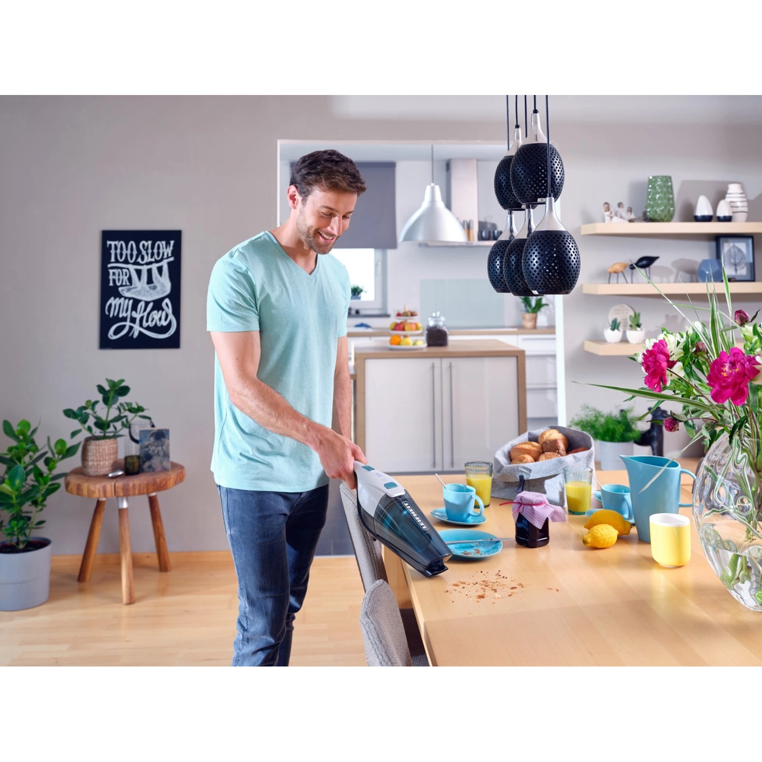 Mann benutzt Leifheit Akku-Staubsauger Rotaro als Handstaubsauger am Tisch.