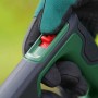 Detailaufnahme: Hand mit Handschuh bedient roten Schalter am Bosch Akku-Laubbläser.