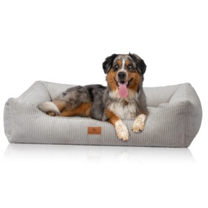 Hund liegt entspannt im hellgrauen Knuffelwuff Hundebett Olivia Cord XXL (120x85cm).