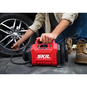 Skil Akku-Kompressor pumpt Autoreifen auf. Das Akkugerät ist rot und hat ein Display.