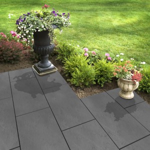 Verlegte, graue Florco Naturstein Klickfliese Stone Schiefer XL auf einer Terrasse mit Blumen.