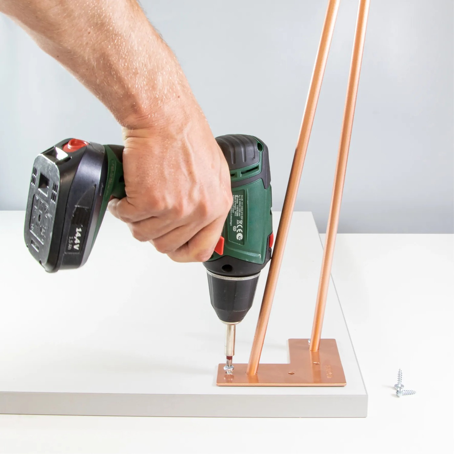 Montage eines schwarzen Wagner Hairpin Leg Möbelbeins mit Akkuschrauber.