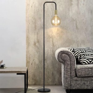 Vintage Stehlampe schwarz-gold aus Metall im Industriestil mit leuchtender Edison-Birne neben Sofa im Wohnzimmer.