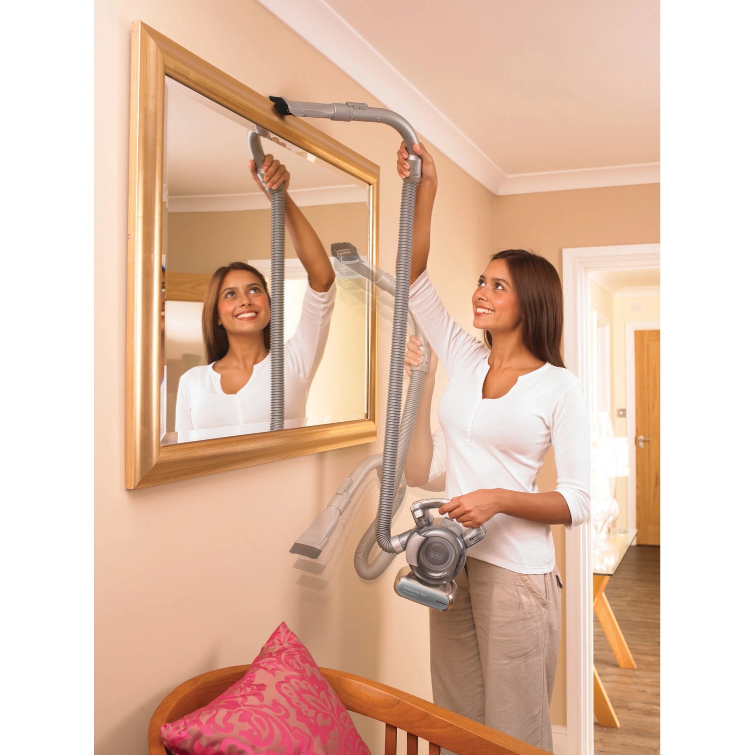 Frau reinigt Spiegel mit Black+Decker Akku-Handstaubsauger Dustbuster Flexi PD1820L.