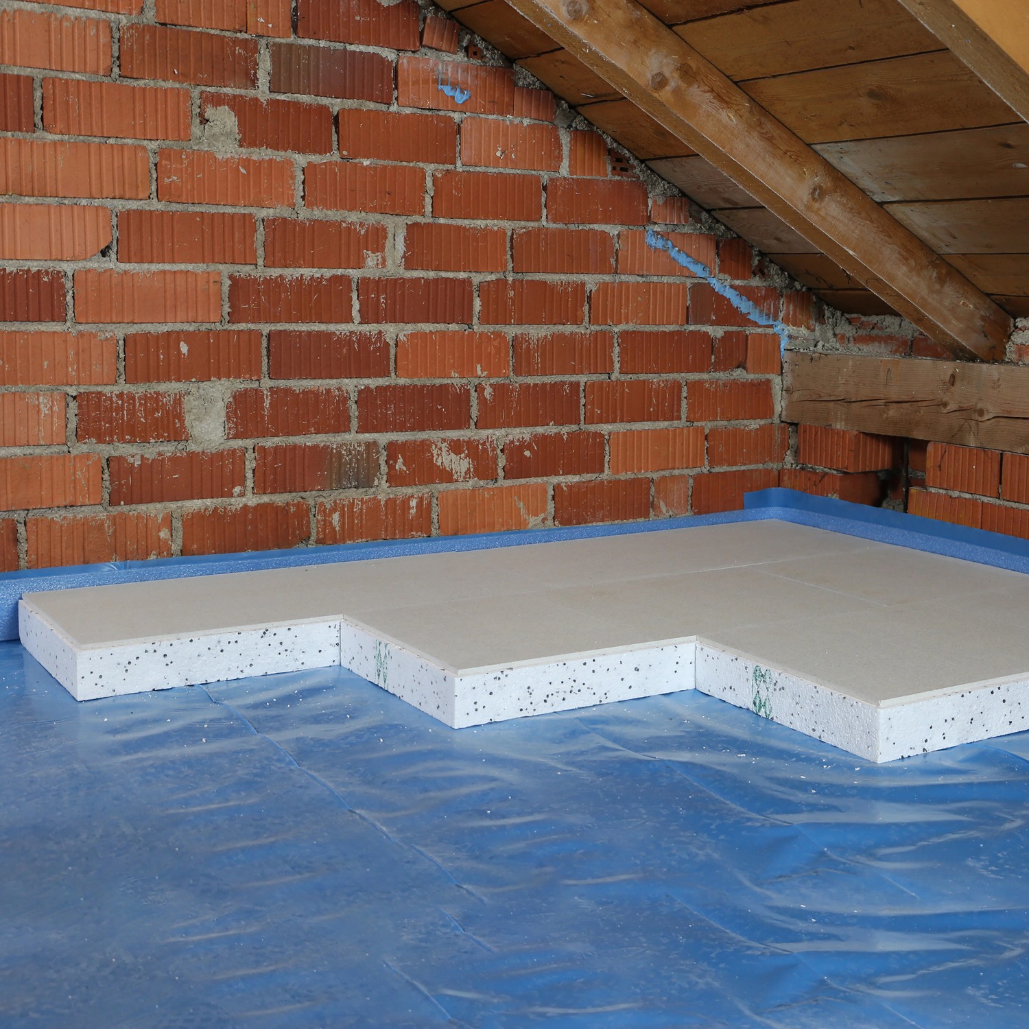 Verlegung von EPS Dachboden-Dämmplatten (120 mm) auf einem Dachboden mit Ziegelwand.