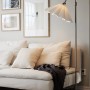 Weiße PR Home Freja Pendelleuchte mit gefaltetem Blütenblatt-Schirm im skandinavischen Design neben Sofa.