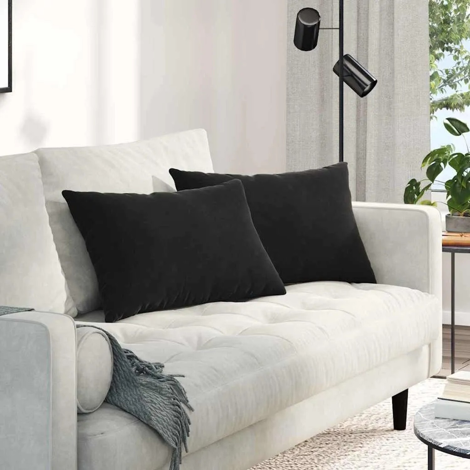 Zwei schwarze Sofakissen (60x40 cm) aus Cordstoff auf einem weißen Sofa.