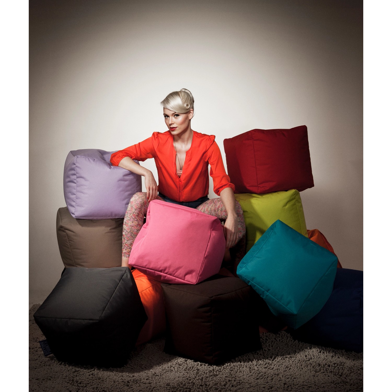 Sitting Point Hocker Scuba Petrol, verschiedene Farben gestapelt, mit Person.