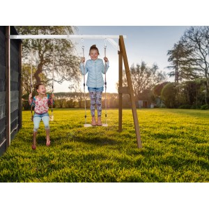 Axi Doppel-Anbauschaukel aus Holz in Braun und Weiß mit zwei schaukelnden Kindern im Garten.