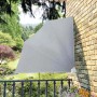 Grauer faltbarer Balkonfächer 140x140 cm als Sonnenschutz auf Balkon mit Ziegelwand und Gartenblick.