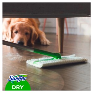 Swiffer Trockentuch-Nachfüllpackung mit Wischer im Einsatz unter Sofa, Hund im Hintergrund.