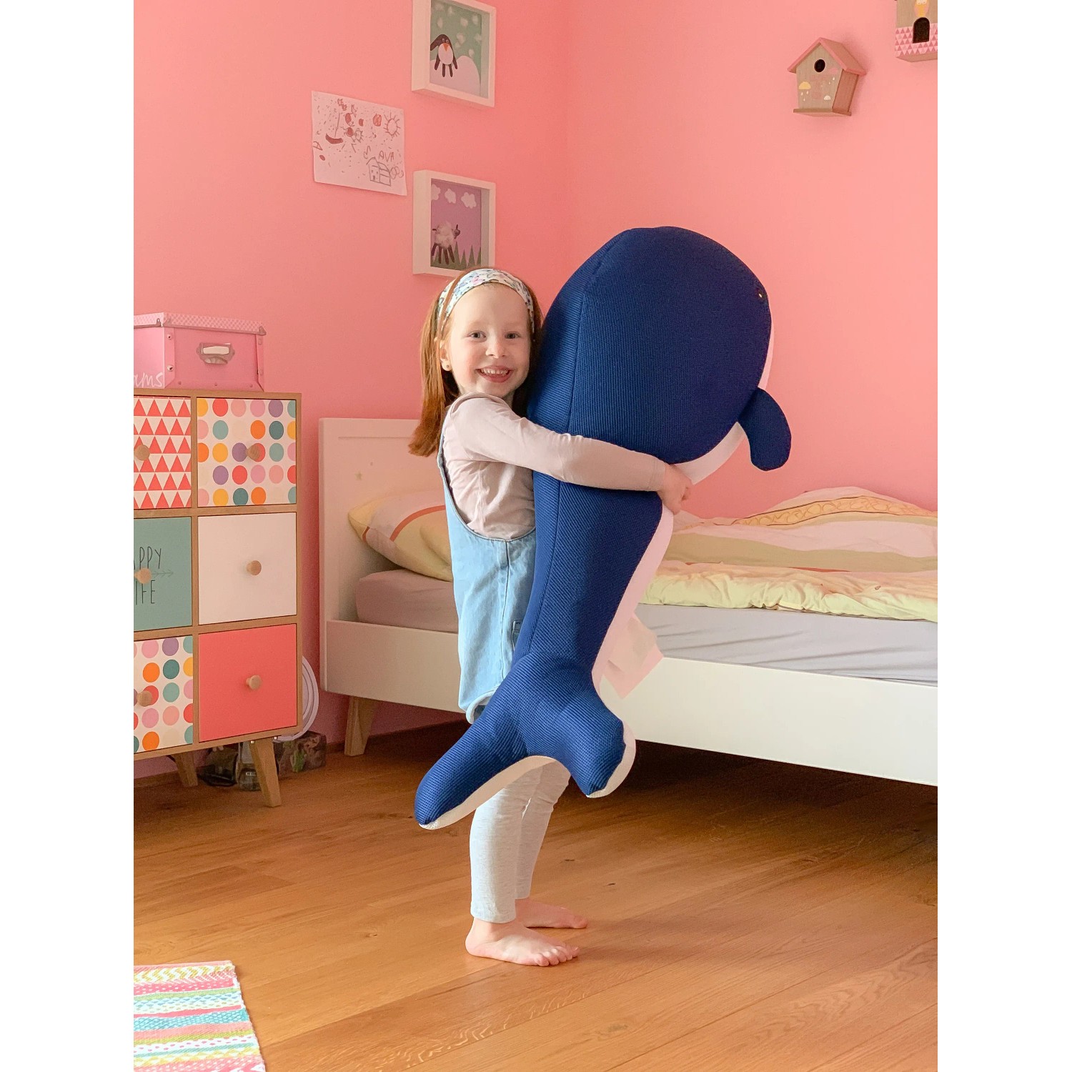 Mädchen umarmt blauen Westmann Pool Buddy Wal als Sitzsack oder Kuscheltier.