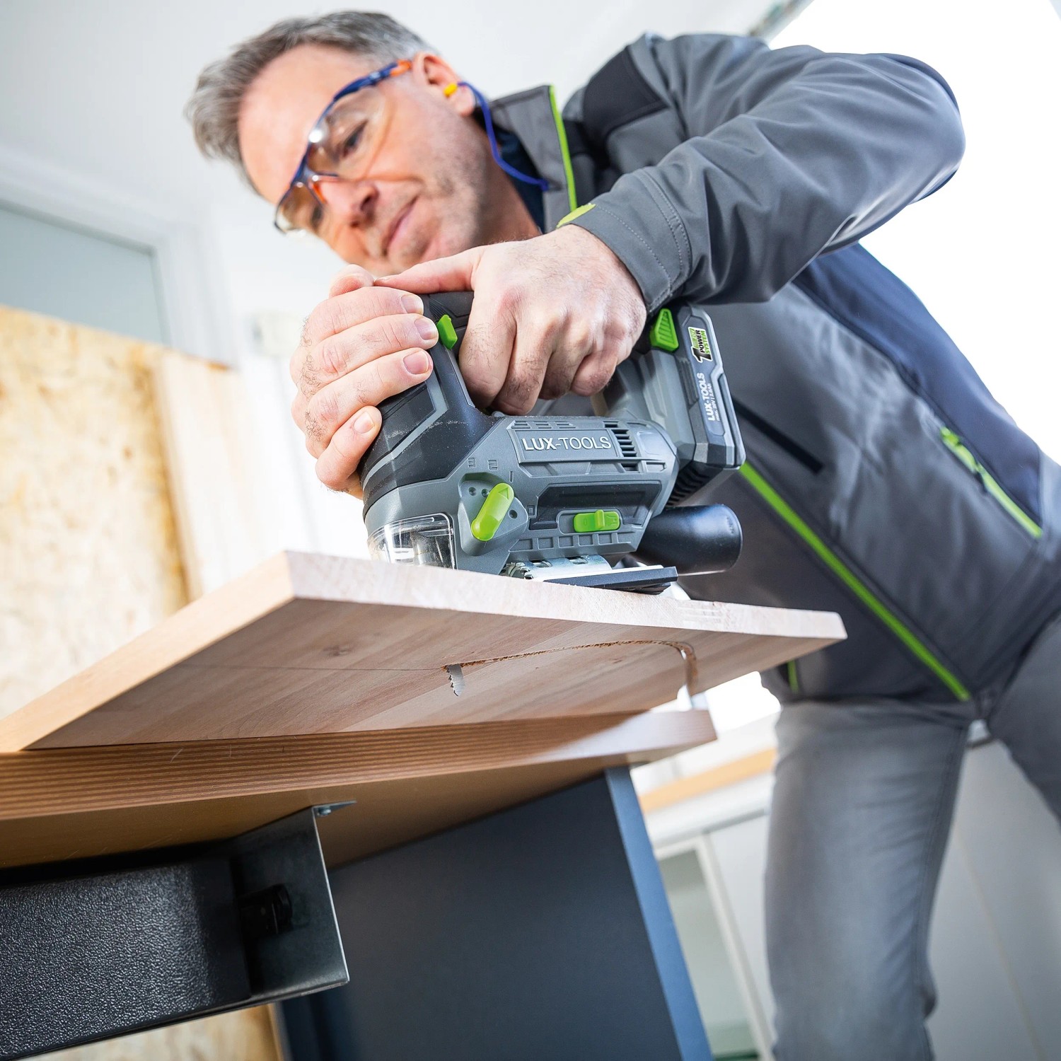 Mann sägt Holz mit LUX Akku-Stichsäge A-ST-20. Stichsäge mit Akku aus dem 1 PowerSystem.