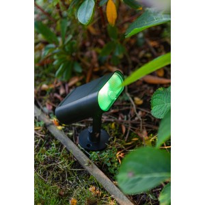 Schwarze Lutec LED Solar-Wegeleuchte Ginbo mit grünem Licht im Garten.