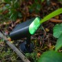 Schwarze Lutec LED Solar-Wegeleuchte Ginbo mit grünem Licht im Garten.