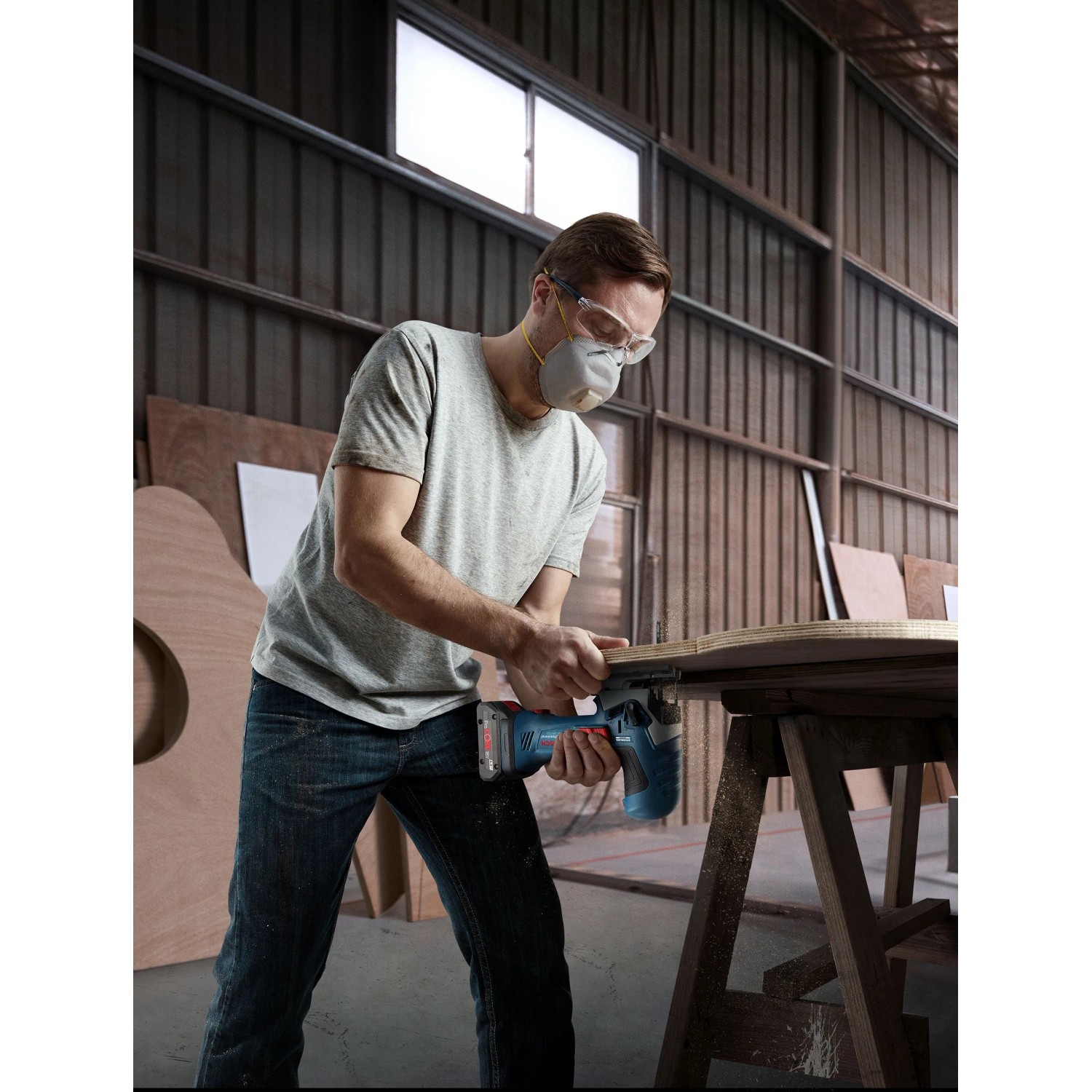 Mann sägt Holz mit Bosch Akku-Stichsäge aus dem 18V Akku-Geräte Kit.