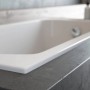 Weiße Rechteck-Acryl-Badewanne CLASSIC SLIM. Nahaufnahme der glatten Oberfläche und des integrierten Ablaufs in modernem Bad.