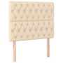 Cremefarbenes Boxspringbett-Kopfteil mit Knopfheftung und Holzfüßen.