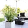 Weißer, hochglänzender Lechuza Cube Premium Pflanzkübel 30x30 cm mit Bepflanzung auf Terrasse.