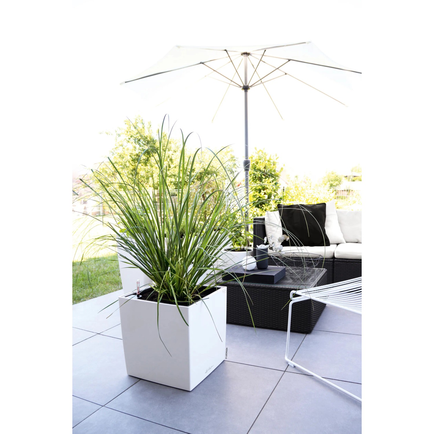 Weißer, hochglänzender Lechuza Cube Premium Pflanzkübel 30x30 cm mit Bepflanzung auf Terrasse.
