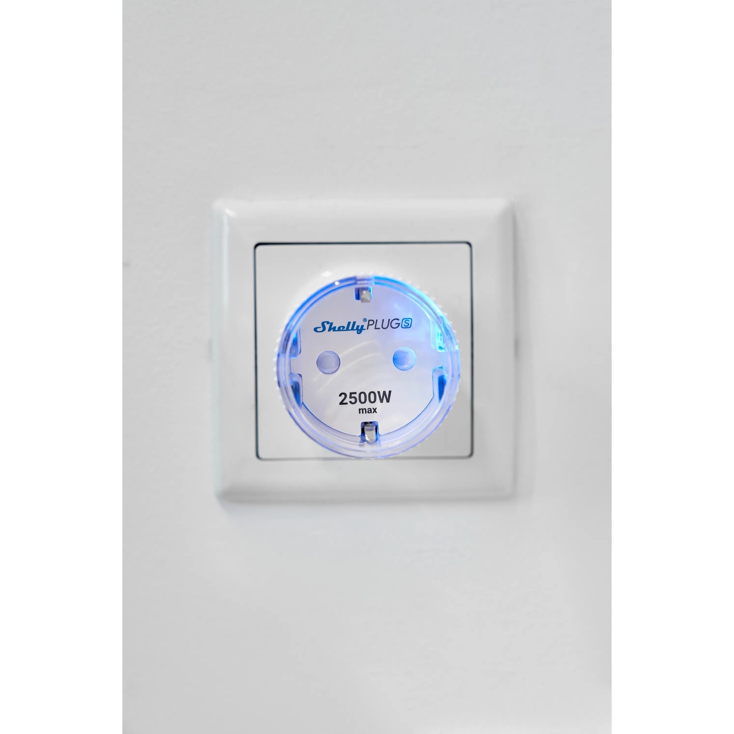 Weißer Shelly Smart-Stecker Plug S Gen3 in einer Steckdose, blaue LED leuchtet.