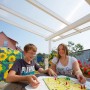 Transparente Acryl Stegdoppelplatte als Terrassenüberdachung, darunter spielende Kinder.