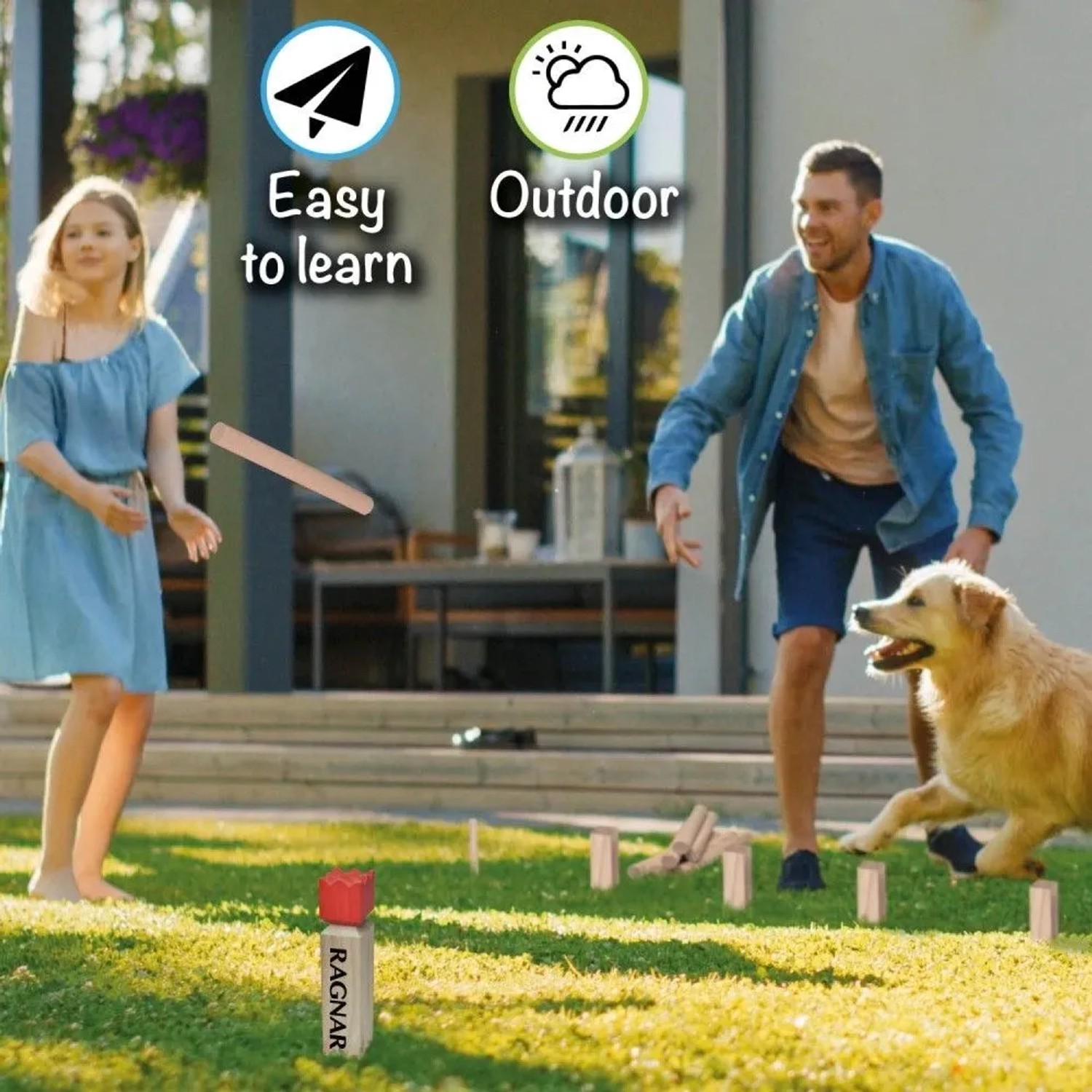Familie spielt Wikingerschach Toyfel Ragnar Kubb im Garten mit Hund. Holzklötze und Wurfstäbe.