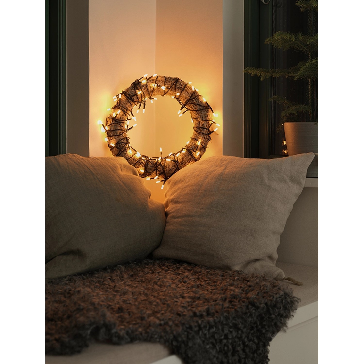 Dekorativer Kranz mit Konstsmide Micro LED-Lichterkette Slim Frosted, bernsteinfarben, im gemütlichen Ambiente.