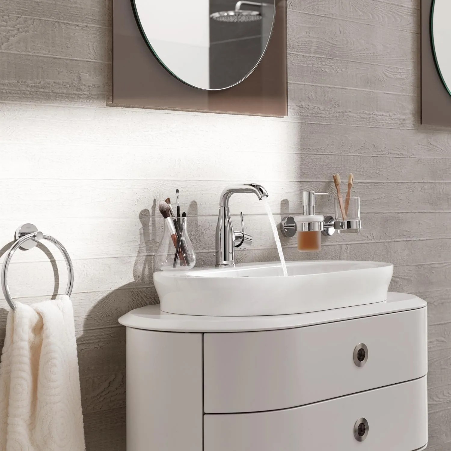 Grohe Essence Waschtischarmatur M-Size in Chrom mit Wasserlauf auf einem weißen Aufsatzwaschbecken.