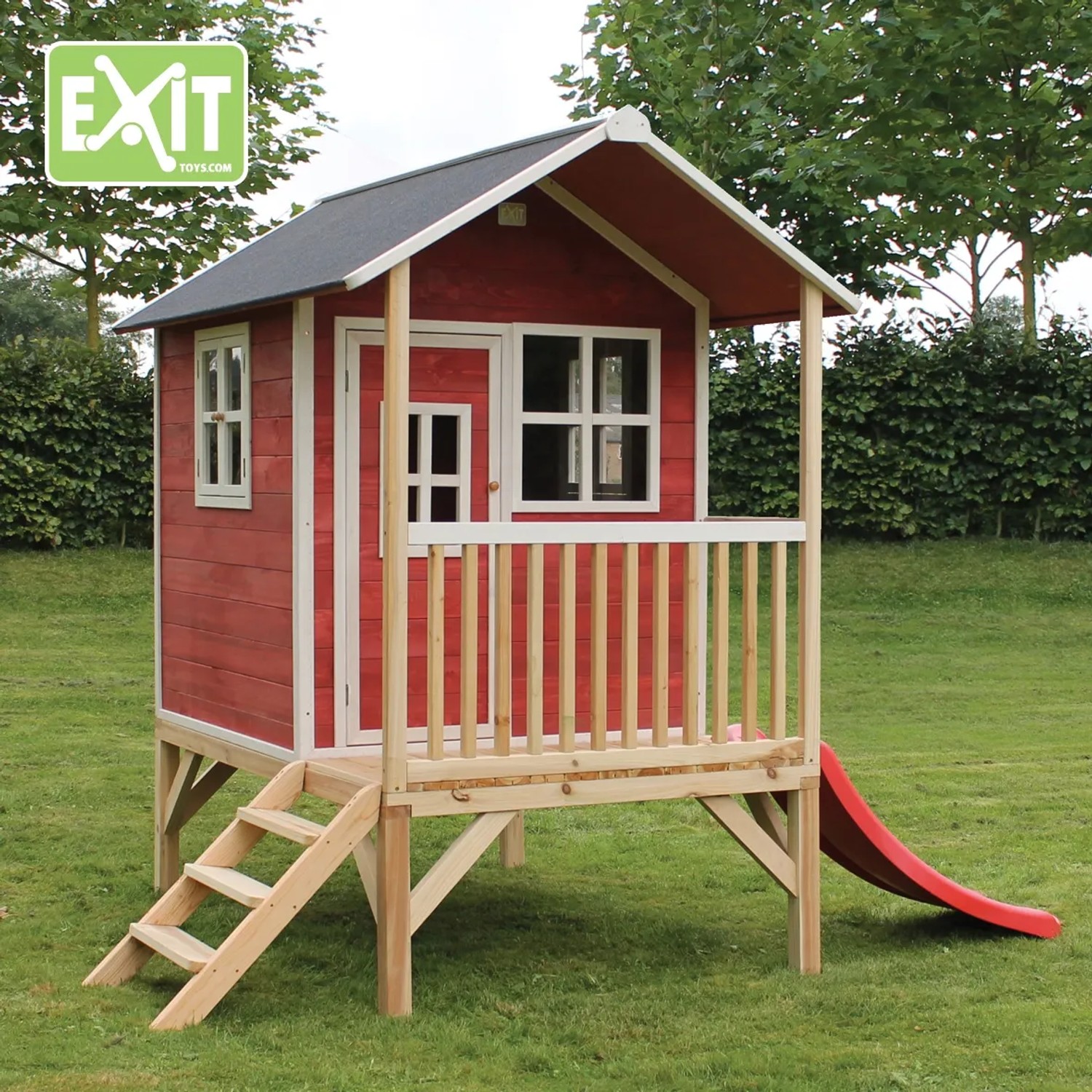 Rotes EXIT Loft 300 Holzspielhaus mit Rutsche und Treppe im Garten.