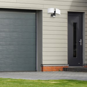 Schwarzer SSC-LUXon LED Außenstrahler mit Bewegungsmelder, 2-flammig, an Hauswand montiert.