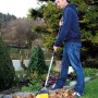 Mann kehrt Laub mit gelbem Sonneck Universalbesen mit Stiel im Garten.