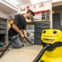 Mann nutzt Kärcher Nass-/Trockensauger mit flexibler Fugendüse zur Reinigung in Werkstatt.