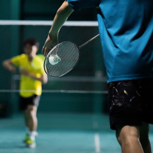 Spieler hält schwarzen Badmintonschläger mit weißem Federball bereit zum Aufschlag. Badminton Set für Sport & Fitness.