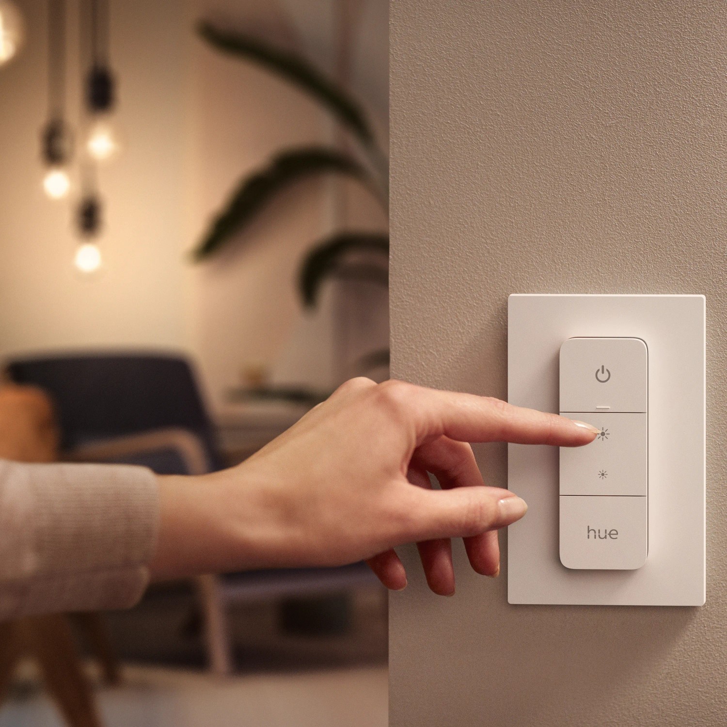 Weißer Philips Hue Dimmschalter V2 an Wand, Finger drückt Taste. Smart Home Beleuchtung steuern.