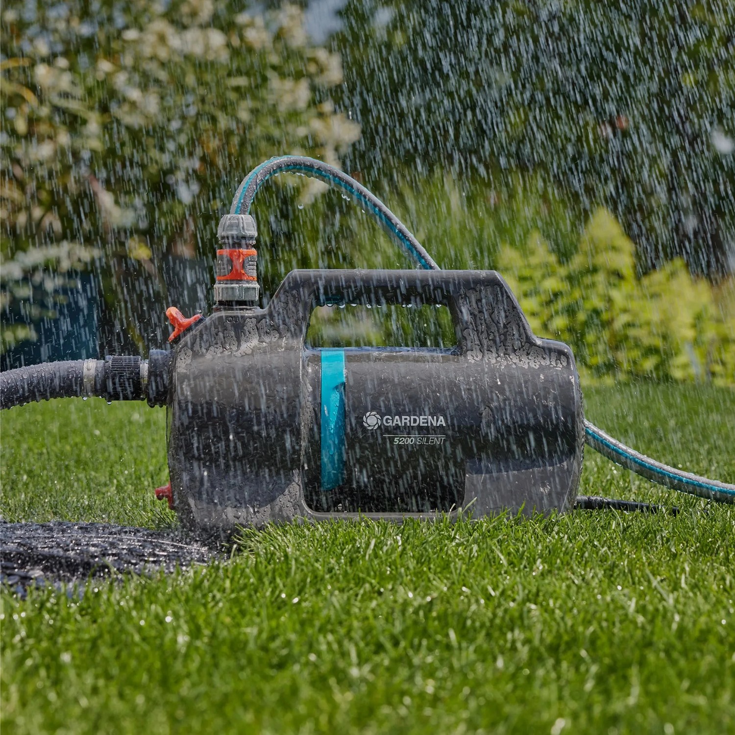 Gardena Gartenpumpe-Set 5200 Silent mit Schlauch und Zubehör im Einsatz auf Rasen.